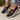 Chaussures noires Beatrix, portées avec jean, fond bois et fleurs
