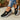 Chaussures noires Beatrix, portées avec jean retroussé, fond bois clair