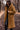 Manteau teddy brun caramel sur fond forestier